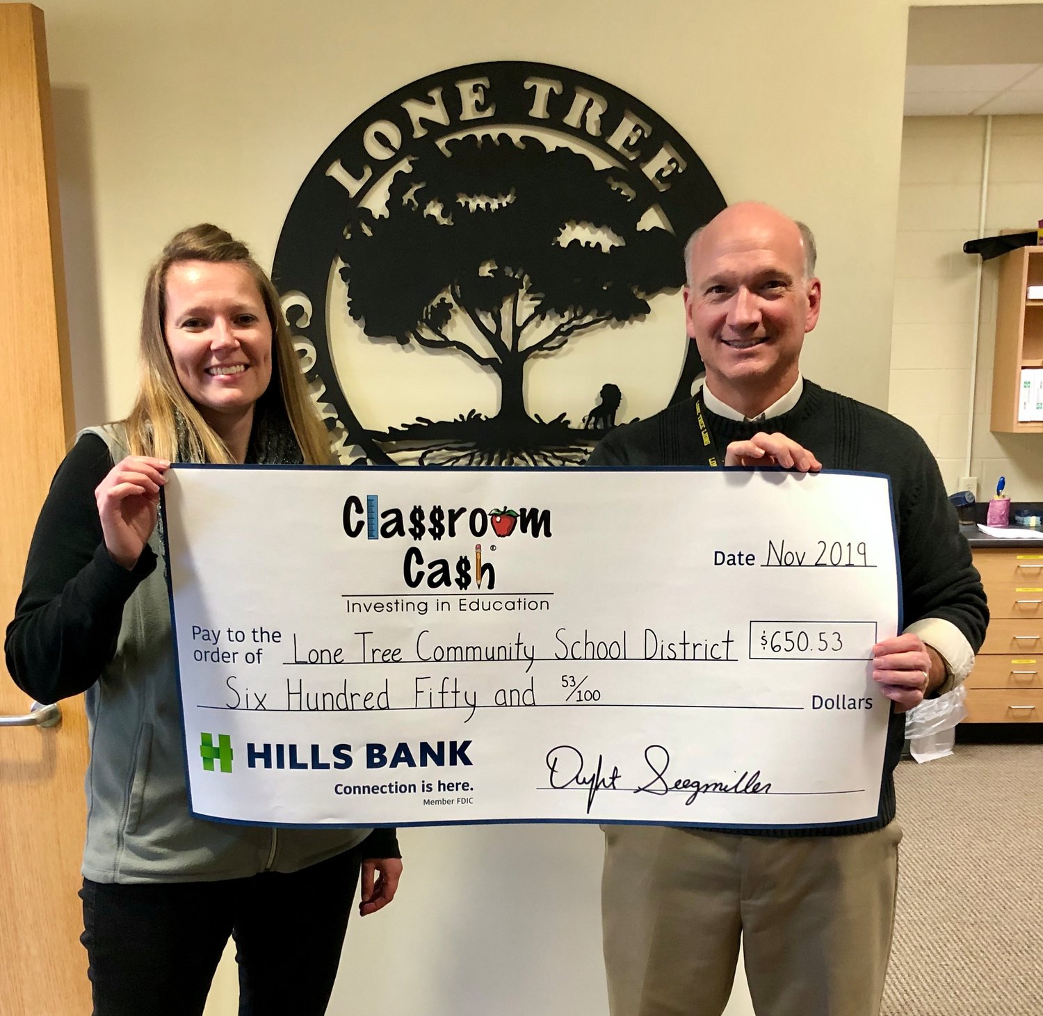 Jenni Eden (left) from Hills Bank presents Lone Tree Superintendent Ken Crawford with a Classroom Cash check for $650.53.